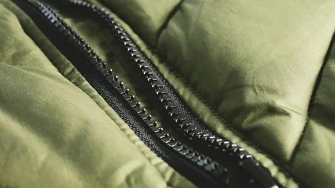 Close-up of a black zipper on an olive green puffer jacket.  Stock Footage 346188936