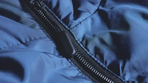 Close up of a black zipper puller on a blue puffer jacket.  Stock Footage 346191049