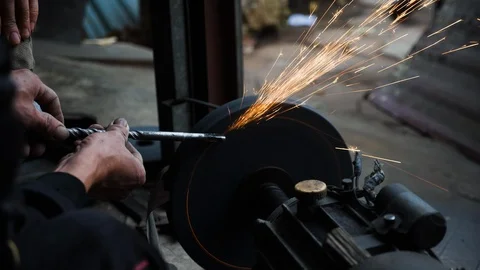 Close up of blacksmith sharpening flat piece of steel as sparks fly out in air Stock Footage 147371274