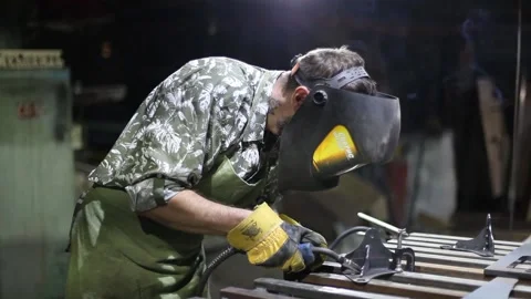 Close-up blacksmith welder in protective mask works with metal using a welding Stock Footage 139586476