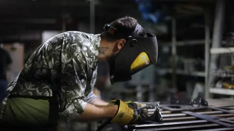 Close-up blacksmith welder in protective mask works with metal using a welding Stock Footage 139589082