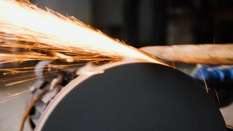 Close up of blacksmith working on flat piece of steel against sharpening wheel Stock Footage 147371840