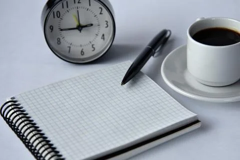 Close-up of a blank notepad with a black pen and a cup of coffee on a white b Stock Photos