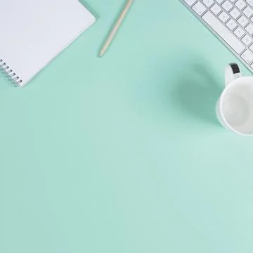 Close up blank notepad pencil cup keyboard turquoise background with space text Stock Photos