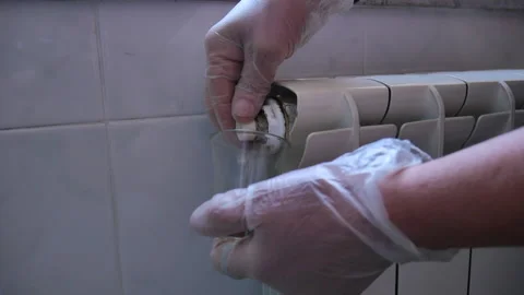Close up of the bleeding of water from the valve of the radiator by technician Stock Footage 153606953