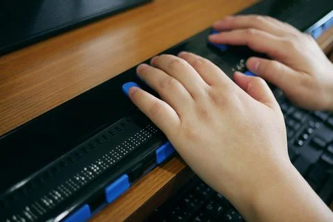 Close-up blind person hands using computer with braille display Фото