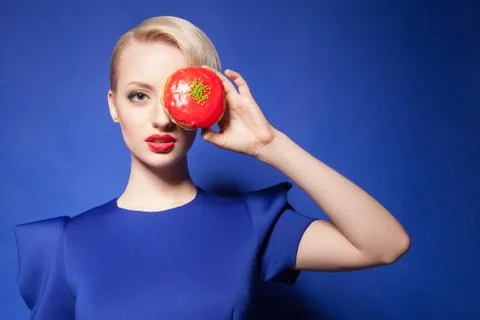 Close-up of blonde-haired model with red donut covering eye Foto stock