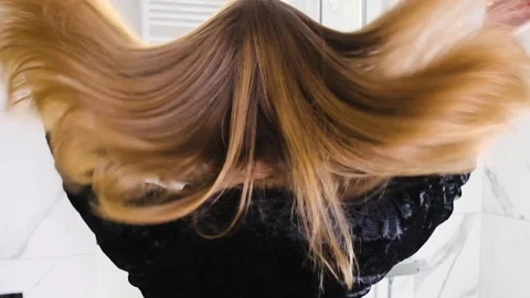 Close-up of a blonde tossing her long, shiny hair in slow motion, beauty routine 스톡 동영상 300040135