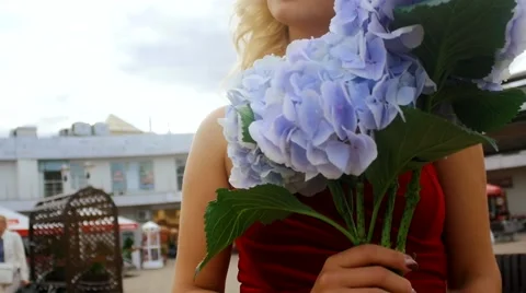 Close-up of blonde woman in a red dress with a bouquet of flowers in their hands Stock Footage