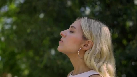Close up of a blonde woman taking a deep breath in the park. Stock Footage 210892124