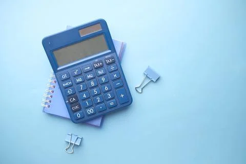 Close up of blue calculator and notepad on color background 写真素材