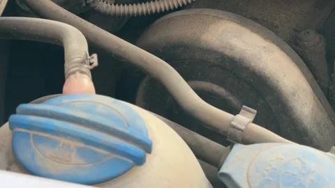 Close-up of blue caps on windshield washer and coolant reservoirs inside a dusty Vídeos de archivo 337115101