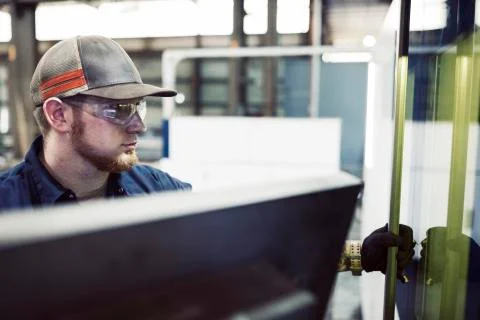 Close-up of blue collar worker using machinery in steel factory Fotos de archivo