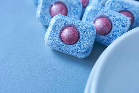 Close-up of blue dishwasher tablets on blue background. Stock Photos