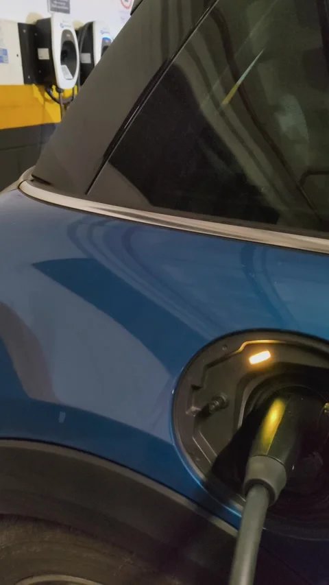 Close-up of a blue electric car plugged into a charging station. Stock Footage 313299752