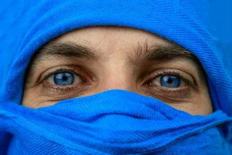 Close up of the blue eyes of a man whose face is covered with a blue bandage Stock Photos