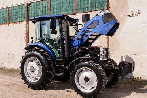 Close up of a blue farm tractor with engine exposed for repair in a bright ou Stock Photos