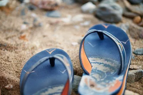 Close up of blue flip flops resting on sandy beach during summer vacation Stock Photos