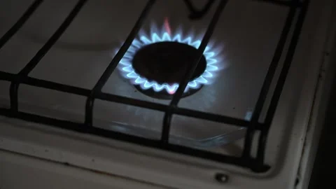 Close-up of a blue gas flame burning on a kitchen stove burner in the dark. Stock-Footage 333581615