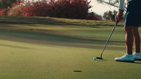 Close up of a blue golf ball rolling across the putting green toward the hole Stock Footage 340990972