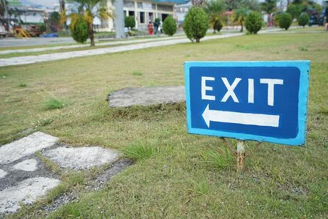 Close up Blue Hand-painted Exit arrow signboard on the ground Stock Photos