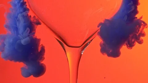 Close up of Blue ink flowing around wine glass  on orange background Stockbeeldmateriaal 122178270
