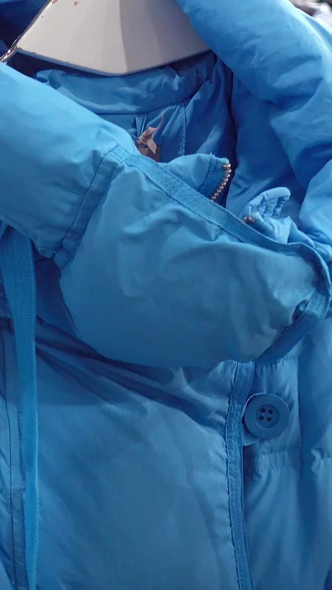 Close-up of a blue jacket being examined by a person. 库存影片 344058234