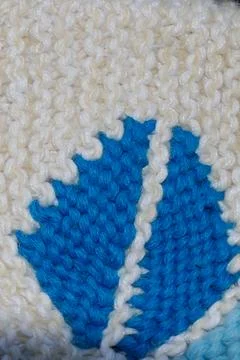 Close up of blue leaf pattern on white knitted fabric with textured yarn st.. Stock Photos