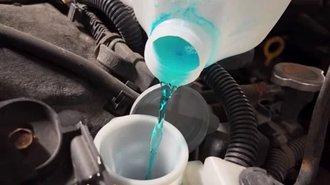 Close-up of blue liquid being poured into a car engine tank Stock Footage 296093276