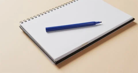 Close up of blue marker on notebook with beige background, in slow motion Stock Footage 331208437