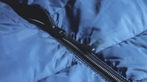 Close up of blue padded jacket with black zipper puller. Stock Footage 346190864