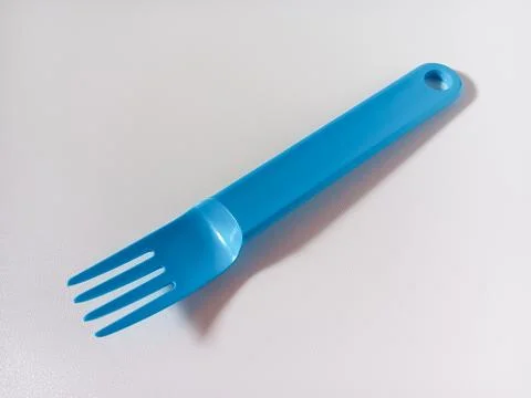 Close up of blue plastic fork isolated on white background. Stock Photos