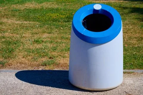Close-up of a blue plastic trash can in a public park. Stock Photos