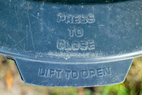 Close up of a blue plastic trash can lid with instructions to press and lift 库存照片