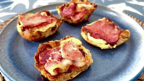Close up of blue plate with bacon strips and melted cheese on toasted bread buns Stock Footage 332219060