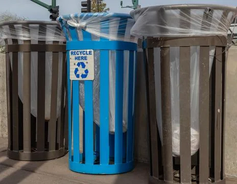 Close up of blue recycle bin with two trash bins in city street Stock Photos