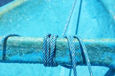 Close up of blue ropes coiled around a weathered blue railing of a boat with  Stock Photos