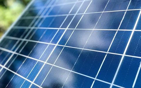 Close up of a blue solar panel reflecting the sky and clouds with green fol.. Stock Photos