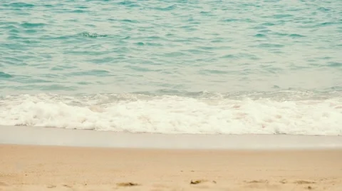 Close up of blue waves spreading on the sand beach and making a white foam Vidéo 62623143