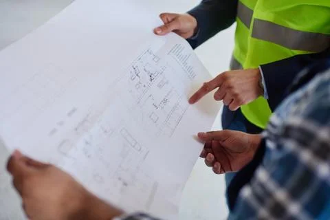 Close-up of a blueprint which two engineers examine. Stock Photos