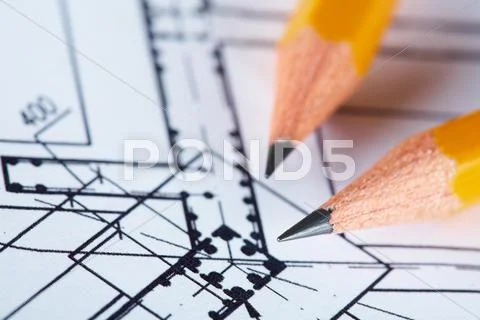 Close-up of blueprints with sketch of project on workplace and two pencils Stock Photos