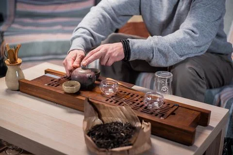 Close-up with a blurred background, hands pour hot fragrant delicious tea from a Stock Photos