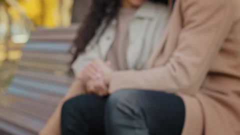 Close-up blurred unrecognizable young couple sitting on bench in city autumn Stock Footage 165825699
