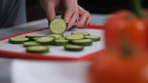 Close-up. On the board is sliced cucumber. Preparing a fresh salad. 4K Slow Mo Stock-Footage 102615959