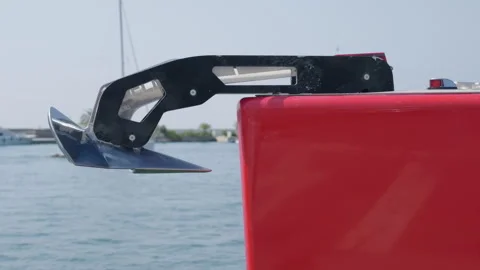 Close-up of a boat anchor and red hull near a stone breakwater with moored Vidéo 344794791