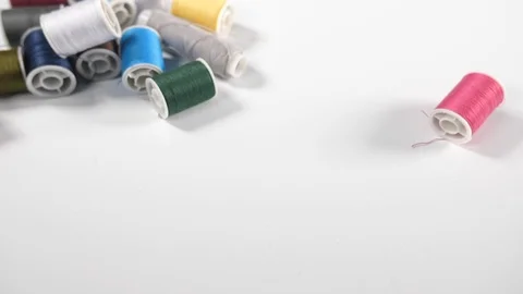 Close up of bobbins of coloured cotton thread with a pink reel falling Stock Footage 89187773
