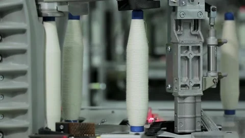 Close-up of bobbins with cotton threads moving along the conveyor .Textile Stock Footage 136170578