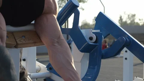 Close-up of a bodybuilder pumping muscles on his arms in an outdoor gym. Stock Footage 288333979