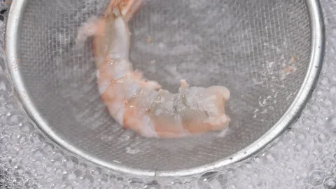 Close up of boiling raw fresh shrimp with a colander in boiling water in a pot.  Video stock 158667425