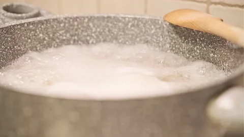 Close Up Boiling Water in the Pan Creates Steam with Wooden Spoon Stock Footage 145218487